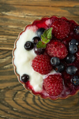 raspberries and blueberries in yogurt sauce in kremanka, top view. Juicy raspberries and blueberries. High quality photo
