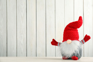Obraz na płótnie Canvas Cute Christmas gnome on table against white wooden background. Space for text