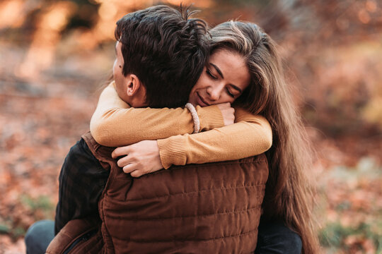Young, romantic couple in tight embrace in the woods. Autumn time