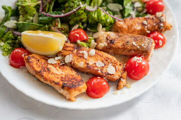 salad dish with slices of baked fried salmon with vegetables and lettuce
