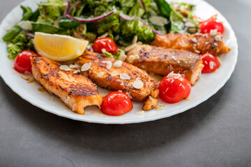 salad dish with slices of baked fried salmon with vegetables and lettuce