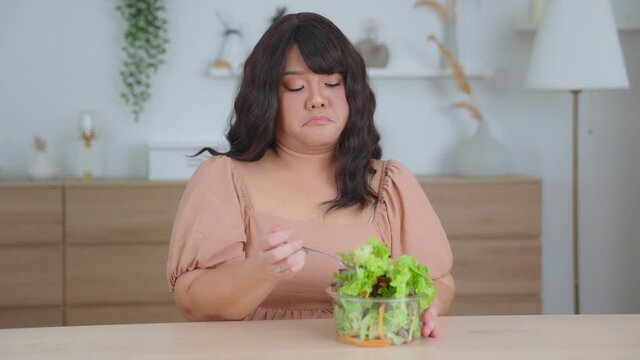 Asian woman oversize big chubby girl not enjoying eat vegetables and salad. Tired of eating  food repeatedly or healthy food that doesn't taste good. overweight girl with Diet and weight loss concept.