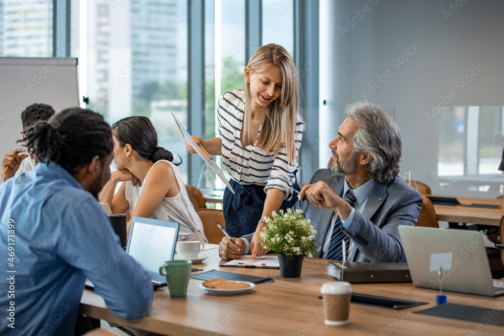 Wall mural Young designer giving some new ideas about project to his partners in conference room. Business people discussing over new business project in office. Business People Working in The Office