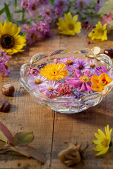 Wasserschale mit duftenden Blüten auf altem Holztisch als herbstliche Dekoration 