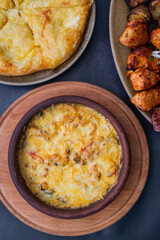 baked suluguni cheese with tomatoes of national Georgian cuisine in earthenware on ketsi