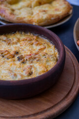 baked suluguni cheese with tomatoes of national Georgian cuisine in earthenware on ketsi