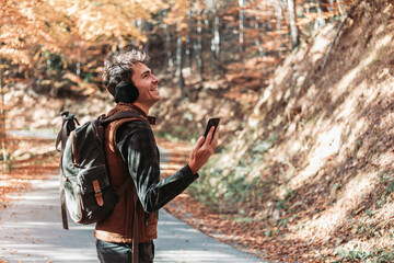 Young man hiker looking at his phone for directions in the woods.