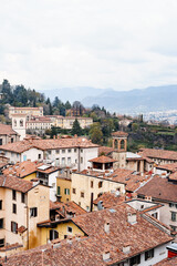 Fototapeta na wymiar Tiled roofs of the old houses of Bergamo against the backdrop of the mountains. Italy