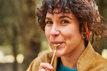 Positive woman licking spoon in countryside