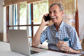 Mature Man Using Mobile Phone And Laptop