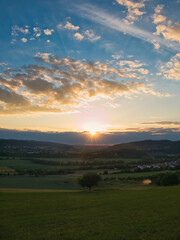 Naklejka na ściany i meble Sonnenuntergang mit schöner Landschaft aus Nordhessen im Vordergrund.