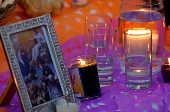 Velas encendidas y vasos de agua para las &aacute;nimas en altar de D&iacute;a de Muertos, M&eacute;xico