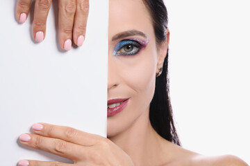 Portrait of woman with evening make-up covers half of face with white sheet