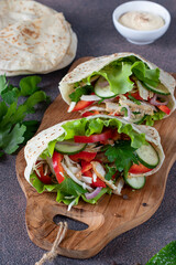 Pita stuffed with chicken, pepper, cucumber and lettuce on wooden board. Middle Eastern cuisine
