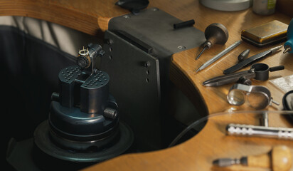 Fototapeta na wymiar Goldsmith at work. Jeweler's workbenche with different tools. Desktop for craft jewelry making with professional tools.