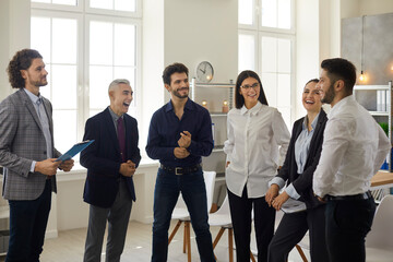 People having a business meeting. Happy young business team having a fun conversation with a mature manager in the office. Concept of sharing experiences between the older and younger generation.