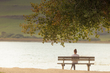 femme assise seule sur un banc devant un lac