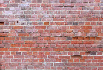 Rough wall background of ancient red brick with fallen out details worn and outdated
