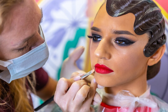 Makeup artist applies lipstick. Hand of make-up master. Make up in process