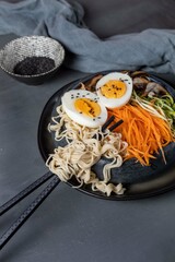 Miso ramen with mushrooms, carrots, zucchini and eggs on a dark background,top view,copy spase