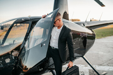 Wealthy young businessman is preparing to use his own private chopper or helicopter to travel to a business meeting.
