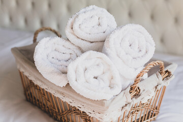 Fototapeta na wymiar Four rolls of white terry towels lie in a wicker basket on a white background. Retro style.