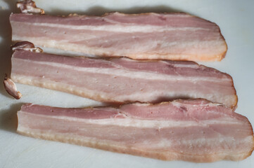 bacon sliced ​​on a white board with copy space to the left and selective focus