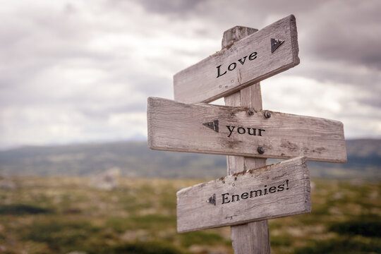 love your enemies text on wooden sign outdoors in nature. Religious and christianity quotes.
