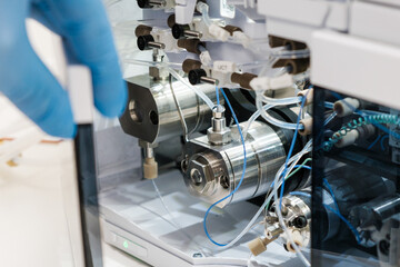 Scientist hand opens the door with binary pump for mixing for HPLC gradient formation and solvent blending. High performance liquid chromatography for separation organic compounds.