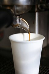 Barista draws milk over a coffee - making latte art for cappuccino