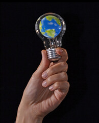 Hand hold a planet earth globe inside a bulb light lamp on global idea concept. ( The planet earth globe is a physical hand made model and photoshop edited by the photographer )