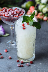Summer fresh cold drinks. Ice lemonade with lemon decorated with cranberries and mint on an outdoor table. lemonade in a glass