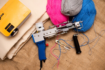 A tufting gun with multicolored yarns and drawing projector for drawing  are laid on a sackcloth....
