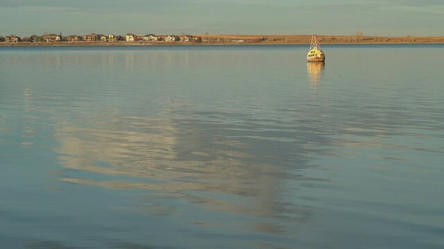 sunset light on a calm lake in November scenery - no wake buoy in Boyd Lake State Park in northern Colorado