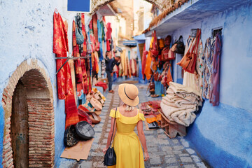 Colorful traveling by Morocco. Young woman in yellow dress walking in  medina of  blue city...