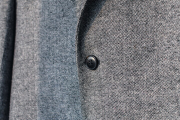 Detail of grey wool blazer with button fragment.  Low DOF. Selective focus.