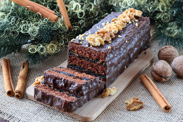 Christmas gingerbread cake in chocolate coating with a plum marmalade filling sprinkled with nuts