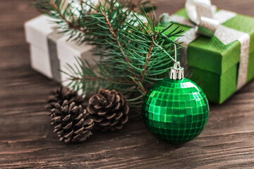 Fototapeta na wymiar Christmas decorations on a wooden background. Gift boxes and green Christmas ball as symbols of Christmas.