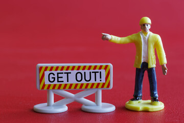 Toy man gestures aggressively next to a Get Out warning sign. The concept of prohibition of access, expulsion and deportation