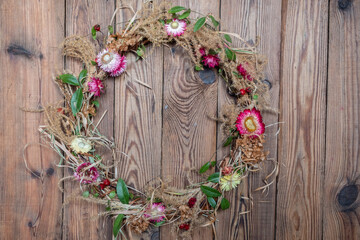 Fototapeta na wymiar Dried floral wreath from natural materials and flowers gelichrizum on dark wooden background.