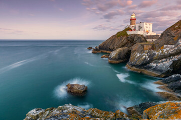 Sunset sea lighthouse rock landscape. Lighthouse sunset view. Sunset lighthouse scene. Sea sunset lighthouse landscape