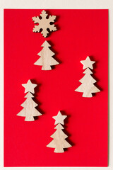 Fototapeta na wymiar wooden christmas tree shapes on red paper with snowflake