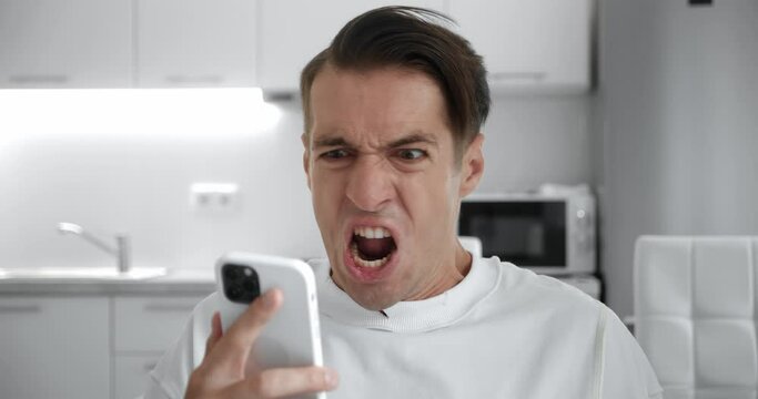 Angry troubled stressed man having problem while using smartphone at home