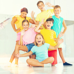 Cheerful friendly preteen boys and girls having fun in choreography class, posing together.