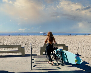 female surfer with bicycle, surfboard and wetsuit