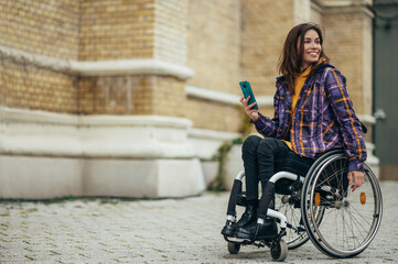 Woman in wheelchair using a smartphone while out in the city