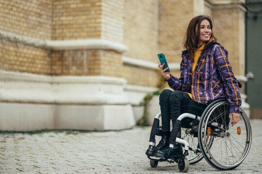 Woman in wheelchair using a smartphone while out in the city