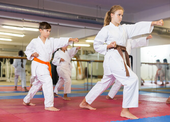 Team of motivated teenagers are engaged in karate in the gym