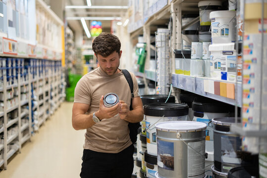 Male buyer reading label on paint tin