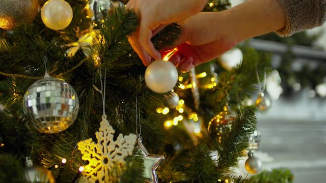 Close-up of a man decorating a Christmas tree. Cropped hand of male decorating and hanging baubles on Christmas tree